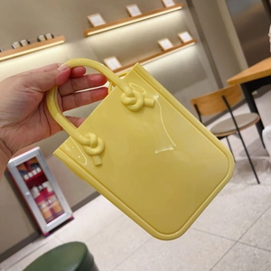 Detail of yellow PVC jelly bag with knot design handle in a casual lifestyle setting