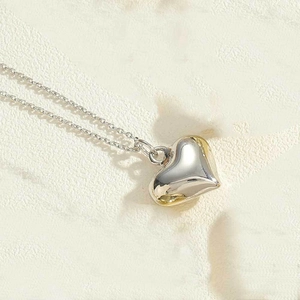 Macro shot of polished 3D heart pendant necklace on minimalist silver curb chain