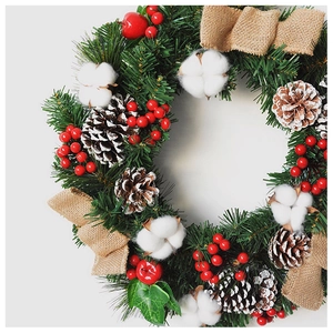 Detail of Christmas wreath with pine cones, red berries, cotton and a linen bow