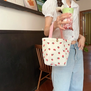Détail de la texture en velours côtelé du sac fraise beige avec anses roses et boucle