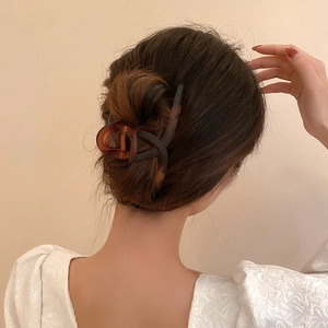 Vue arrière d'un modèle portant une grande pince à cheveux en écaille pour un chignon