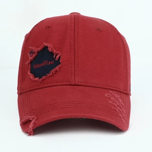 Close-up of distressed red baseball cap with Woodlise embroidery and vintage frayed edges