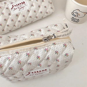 Gros plan sur la trousse fleurie matelassée avec étiquette SOZAKKA et zip