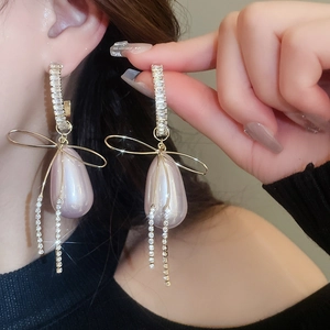 Detailed view of pink pearlescent drop earrings with bow and rhinestone tassels