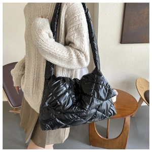 Detail of the black quilted shoulder bag featuring a soft padded texture and puffy nylon finish