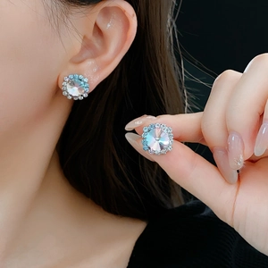 Close-up of sparkling square rhinestone earrings worn by model on dark background