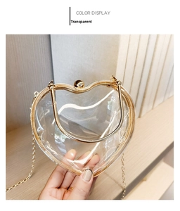 Detail of transparent heart acrylic handbag with gold metal trim and chain strap