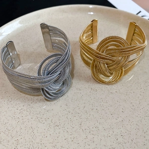 Detail view of gold and silver textured metal cuff bracelets with woven knot design