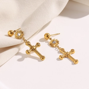 Vue détaillée de boucles d'oreilles croix plaquées or 18 carats avec pendentifs soleil