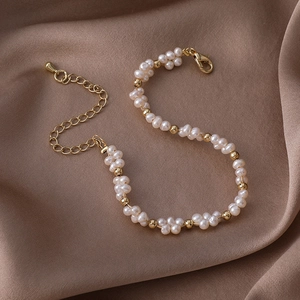 Detailed macro view of baroque pearl bracelet with gold lobster clasp on silk