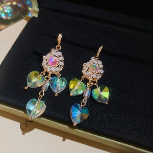 Detailed macro shot of French style gold earrings with AB heart crystals and pearls