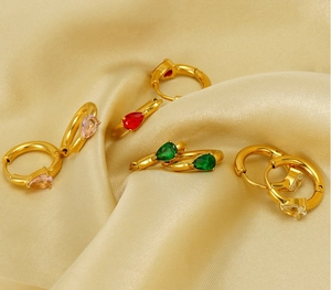 Close-up of gold plated teardrop earrings with colorful zircon stones on satin