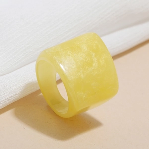Detail view of yellow resin geometric ring with marble texture on white fabric