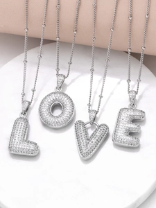 Detailed macro view of four silver letter pendants spelling LOVE with cubic zirconia