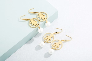 Detail of gold boy and girl silhouette earrings with white pearl pendants