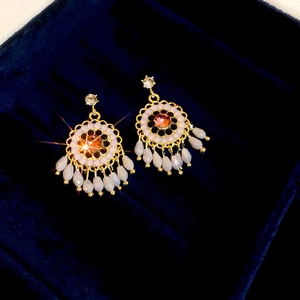 Close-up of vintage flower tassel earring with pink faux gemstone in a velvet jewelry box