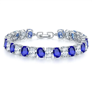 Macro shot of silver tennis bracelet featuring alternating blue and white oval gemstones