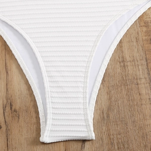 Details des weißen gerippten Stoffes und der Nähte des One-Shoulder-Badeanzugs