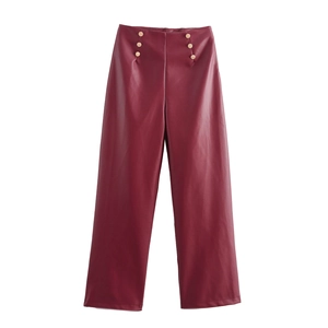 Détail macro du pantalon large en cuir PU bordeaux avec boutons dorés à la taille haute