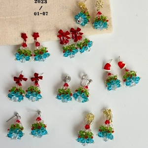 Detailed shot of handmade beaded Christmas tree earrings with red bows and crystal ornaments