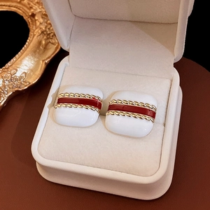 Macro shot of vintage gold-plated square earrings with red enamel in a white jewelry box