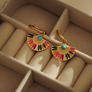 Détail de boucles d'oreilles bohèmes en émail coloré avec perle turquoise sur velours