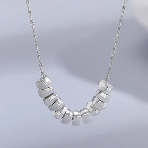 Macro shot of silver beaded pendant featuring faceted metallic balls on a fine link chain