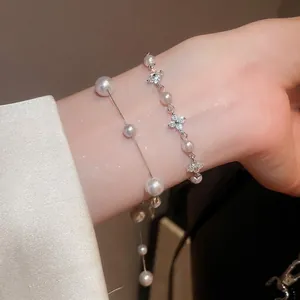 Elegant layered irregular pearl bracelets with silver flower accents on a model wrist