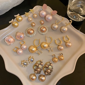 Flat lay of vintage gold-tone earrings with pearls and rhinestones on a wavy tray