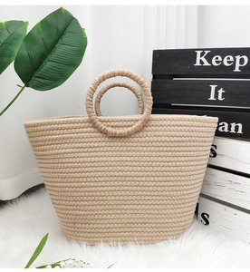 Detail of a beige woven straw beach tote bag with round handles on a white soft rug