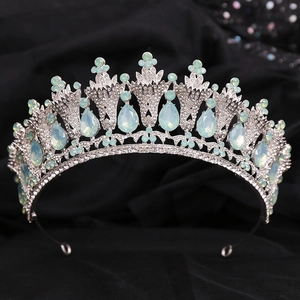 Close-up of a silver baroque crown featuring light blue teardrop gems and rhinestones
