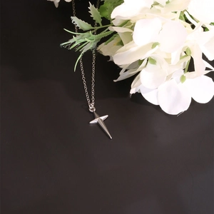 Close-up of a silver cross star pendant with a minimalist chain on a black background