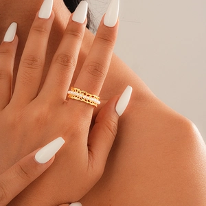 Detailed view of gold lace hollow ring with embedded white pearls on a female finger