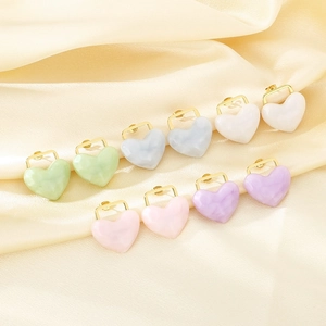 Close-up of colorful resin heart earrings in 18K gold plated steel on silk fabric