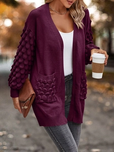 Detail of burgundy knit cardigan featuring bubble texture sleeves and large side pockets
