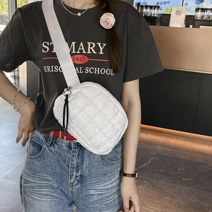 Detail of white quilted nylon crossbody bag with wide strap and black zipper accents