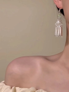 Gros plan de boucles d'oreilles à pompons argentés avec motifs ajourés sur un mannequin