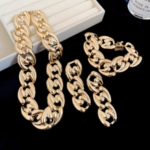 Detailed view of luxury gold thick chain jewelry set on black background with perfume