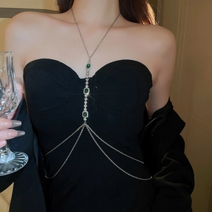 Détail d'une chaîne de corps argentée avec strass émeraude sur une robe de soirée