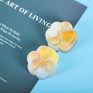 Detailed macro view of two translucent cat paw crafts with warm orange gradient finish