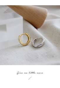 Close-up of minimalist S925 sterling silver and gold hoop earrings on textured linen