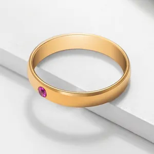 Minimalist gold stainless steel ring with a round pink zircon birthstone on stone stand