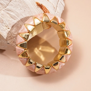Macro detail of geometric acrylic resin bracelet with pink marble texture and gold metal accents