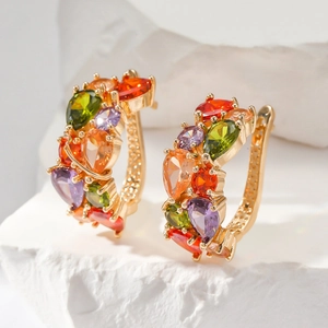 Vue macro de zircons colorés taille poire sur boucle d'oreille dorée sur fond pierre