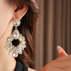 Gros plan d'un modèle portant des boucles d'oreilles dorées avec cristaux et franges