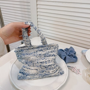 Dettaglio della mini borsa in tweed bianco e blu con trama intrecciata ed etichetta