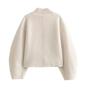 Close-up of beige textured knit sweater fabric showing detailed collar and shoulder seams