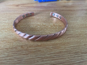 Close-up of copper energy therapy bracelet showing twisted texture and magnetic ends