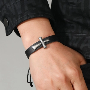 Close-up of a men's woven black leather cross bracelet with silver metal detail on wrist