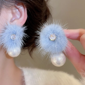 Macro view of light blue pompom earring with zircon inlay and large white pearl